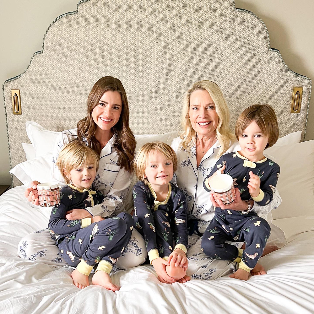 two women with coffee sitting on bed with three little boys