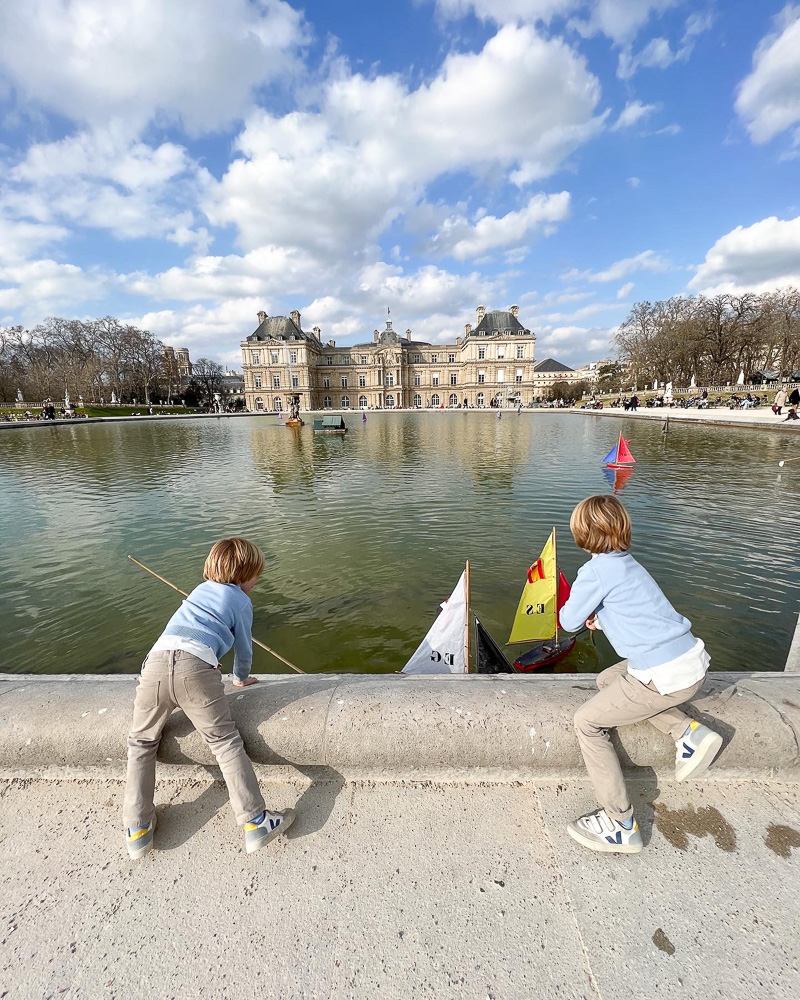 two young boys playing with toy sailboats in paris