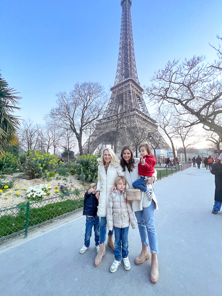 two women standing with three little boys in front of the eiffel tower