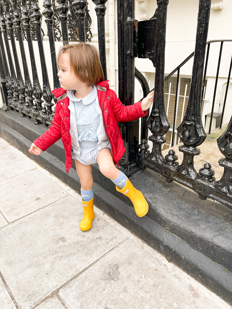 toddler boy in red coat and yellow rain boots