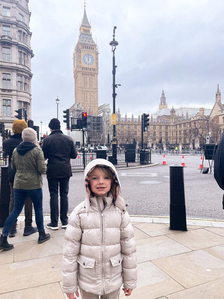 little boy bundled up in front of big ben london