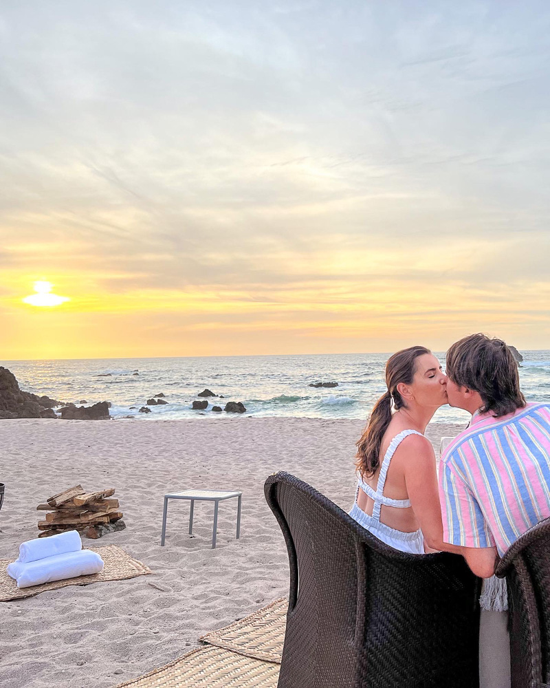 couple kissing at sunset beachside dinner