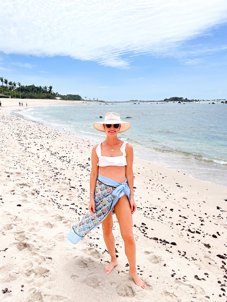 woman in swim suit and sarong standing on the beach