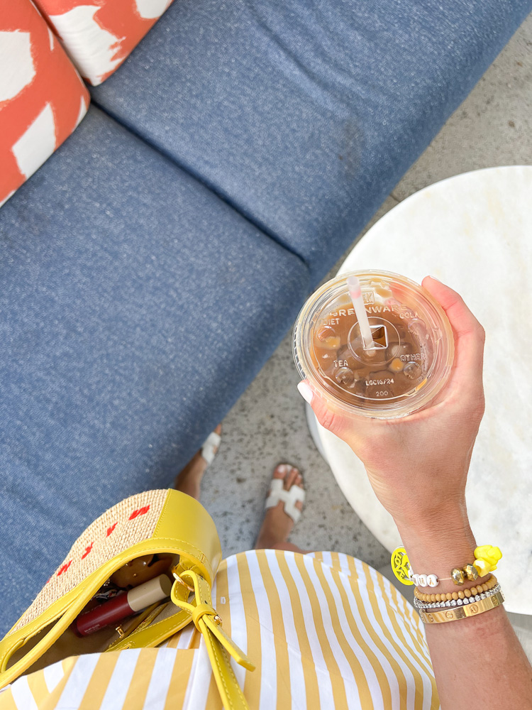 woman in striped shirt holding iced coffee
