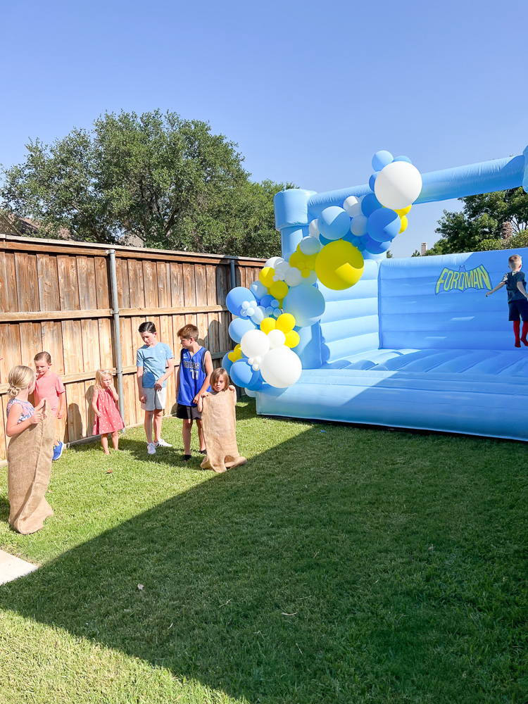 scene of backyard with blue bounce house and balloon garland