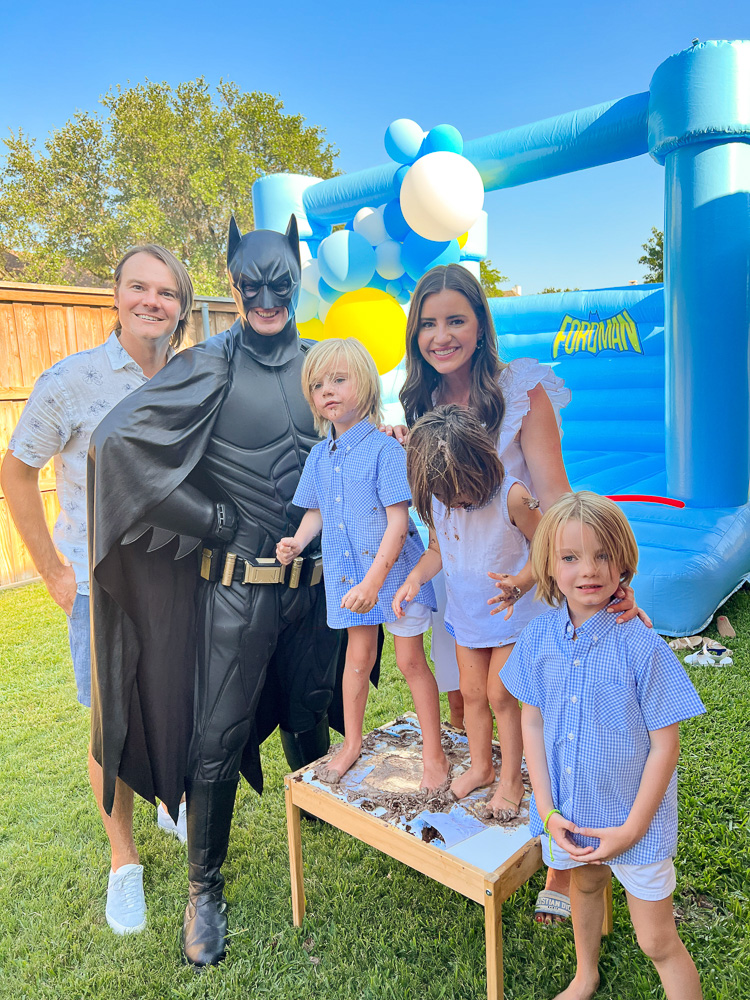 batman posing with three boys and their mom and dad