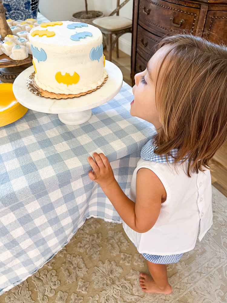 little boy looking at blue and yellow batman cake