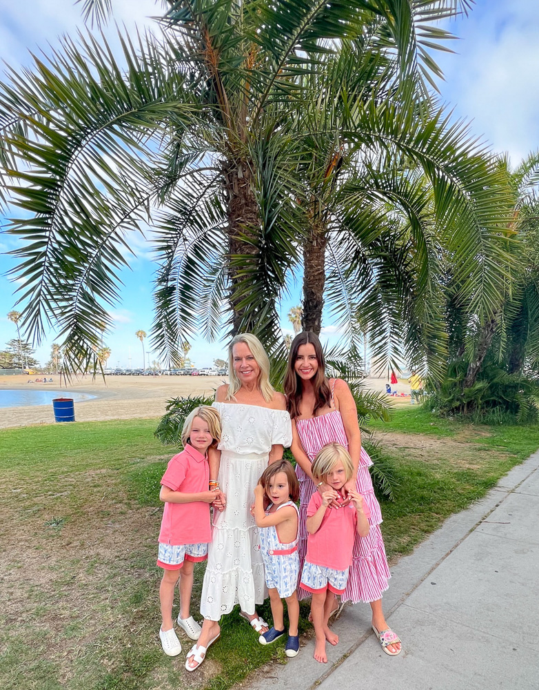 two women with three little boys standing next to palm trees