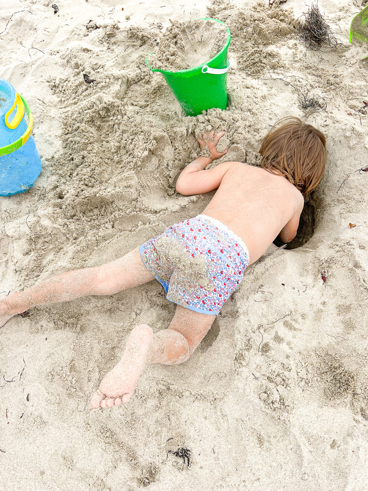 little boy digging hole in the sand at the beach