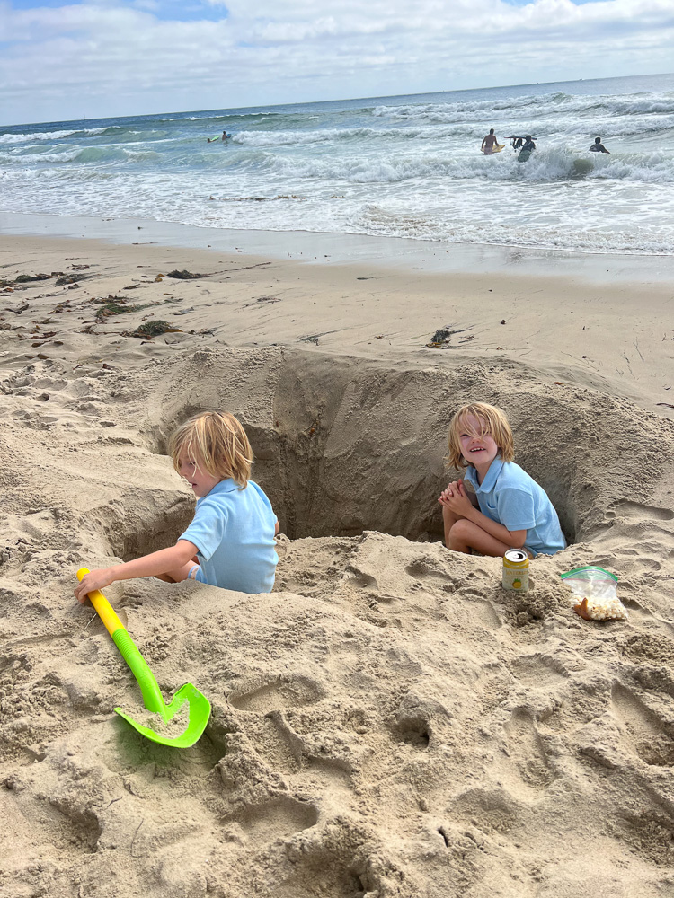 two little boys digging a big hole at the beach