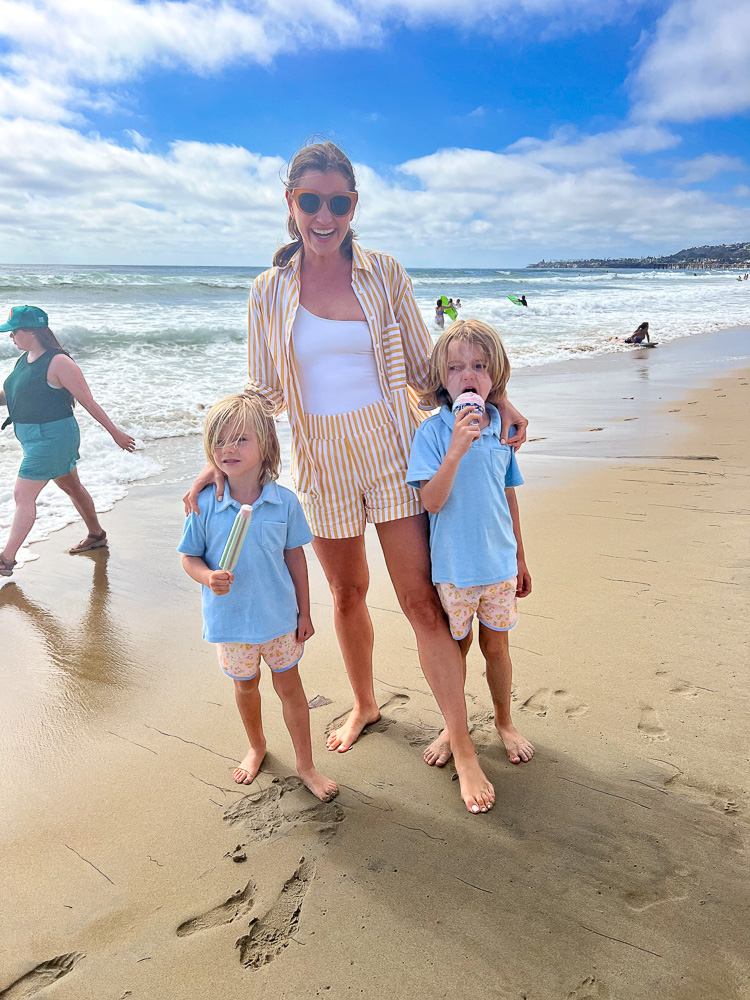 woman walking on the beach with two little boys eating popsicles