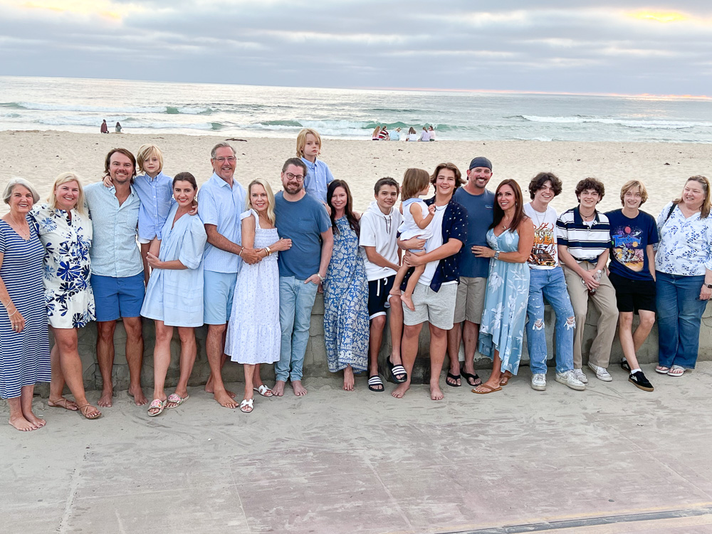 large family group standing in front of sea wall at the beach
