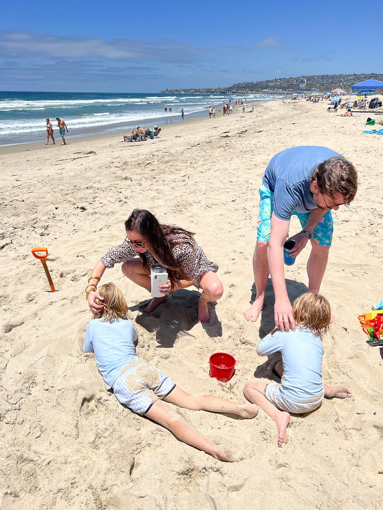 family digging in the sand at the beach