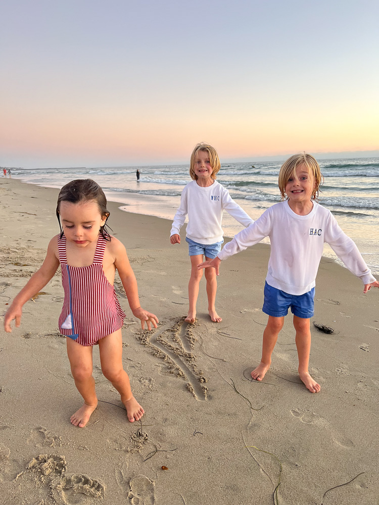 three little boys in wet clothes standing in the sand at the beach