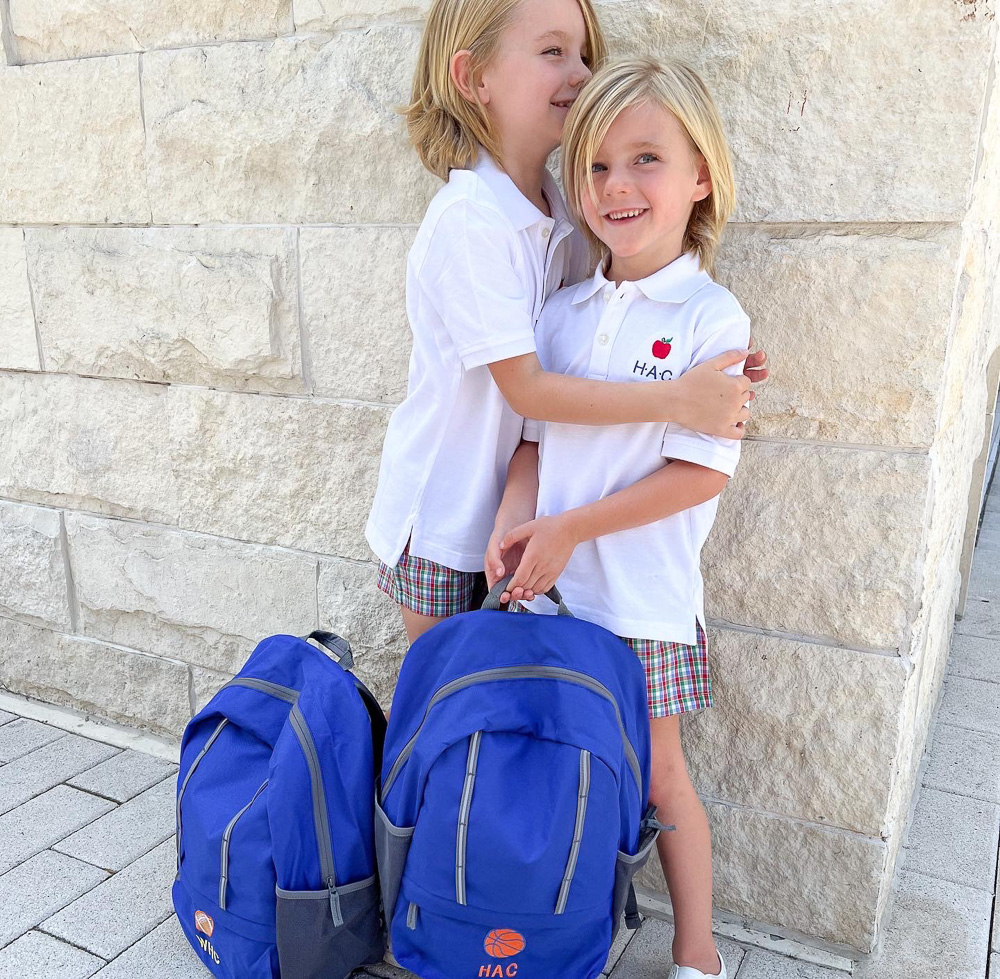 two brothers standing with blue backpacks and apple polos