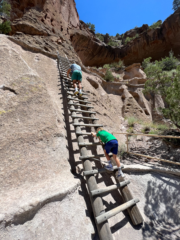 two little boys climbing tall ladder at bandelier national park