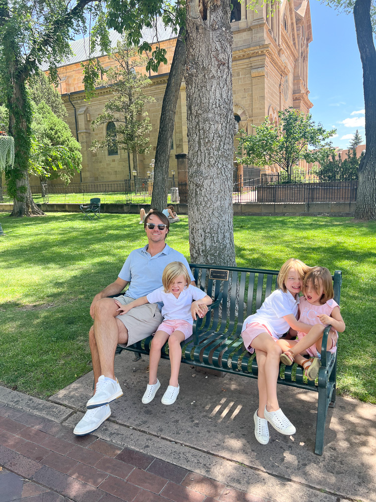 dad with three little boys sitting on park bench