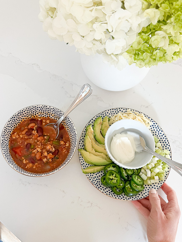 a bowl of chili and a side dish of chili toppings