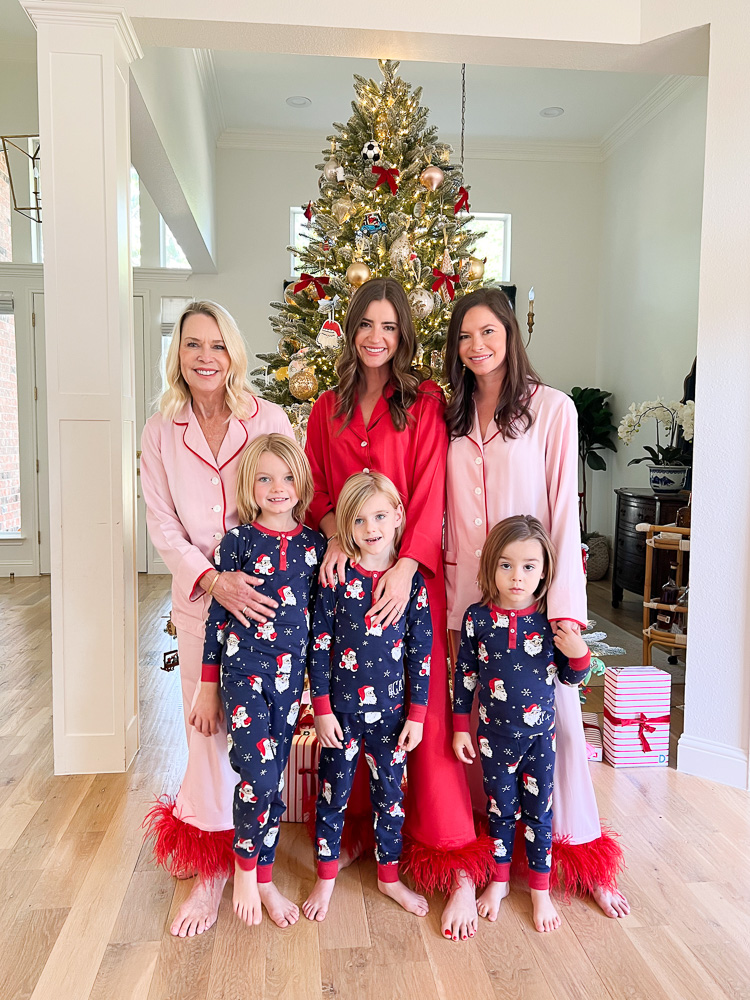 three women and three little boys in matching christmas pajamas standing in front of christmas tree
