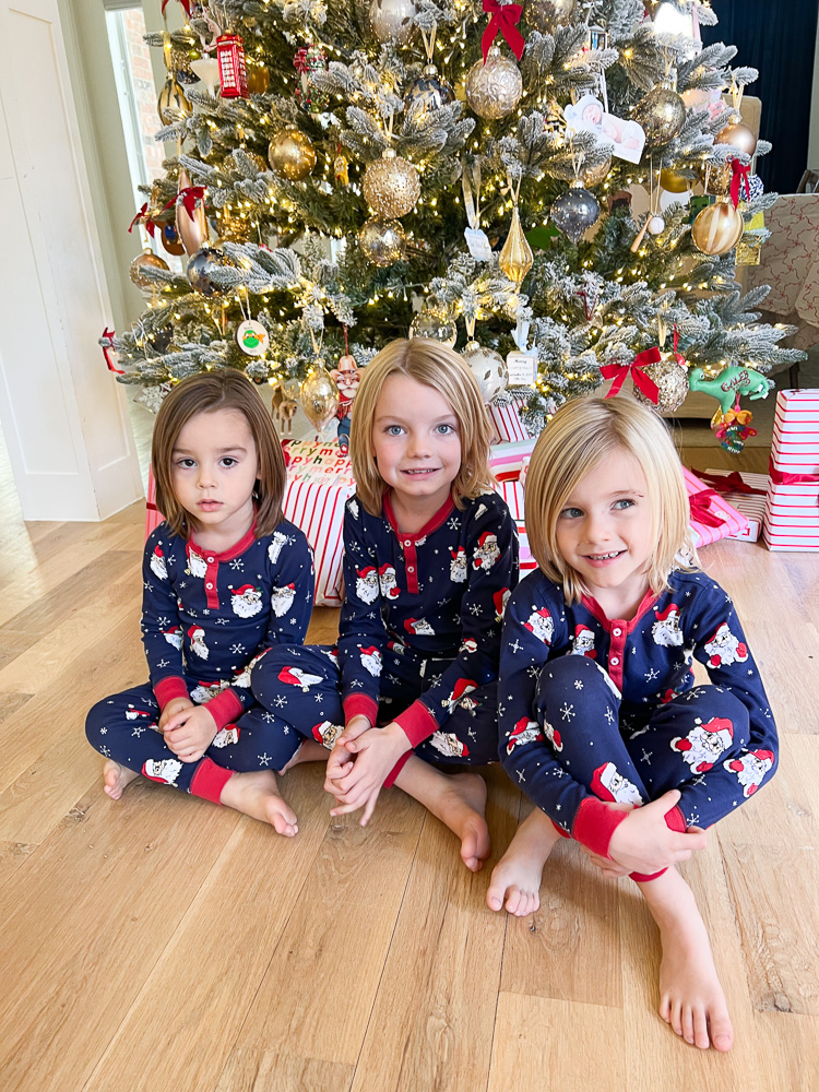 three little boys in matching christmas pajamas sitting in front of christmas tree