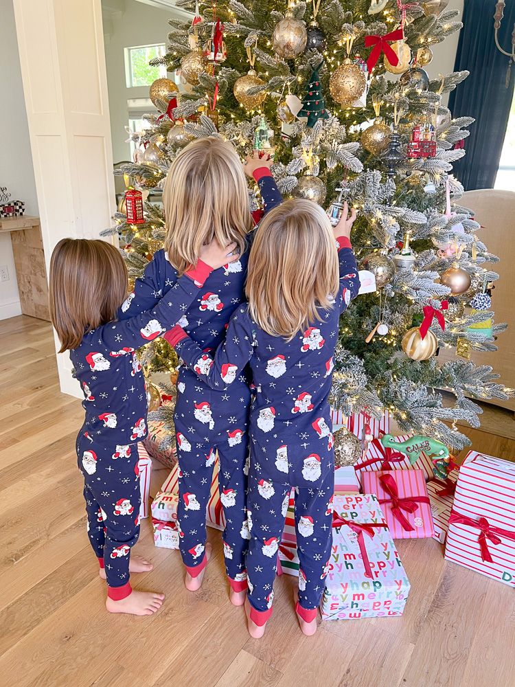 three little boys in matching pajamas standing in front fo christmas tree