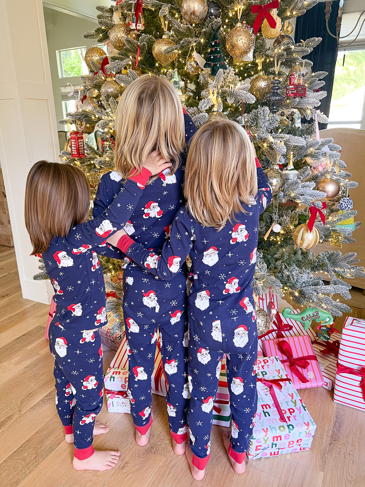 three little boys in matching pajamas standing in front fo christmas tree