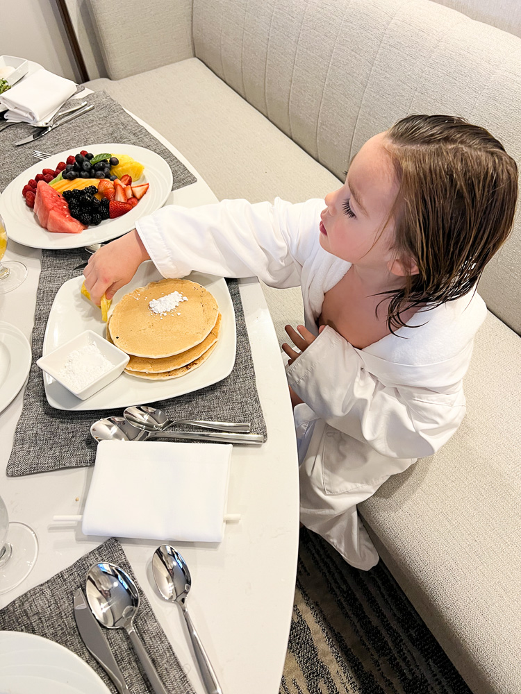 toddler boy in bathrobe eating room service breakfast FS jackson hole