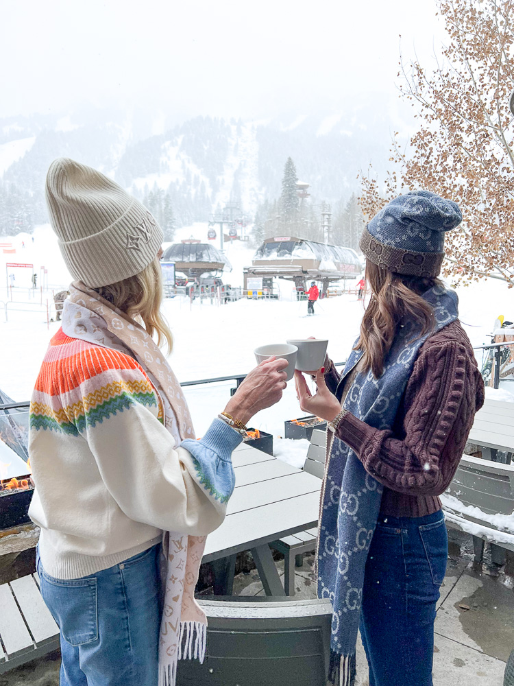 two women with coffee overlooking teton village ski area
