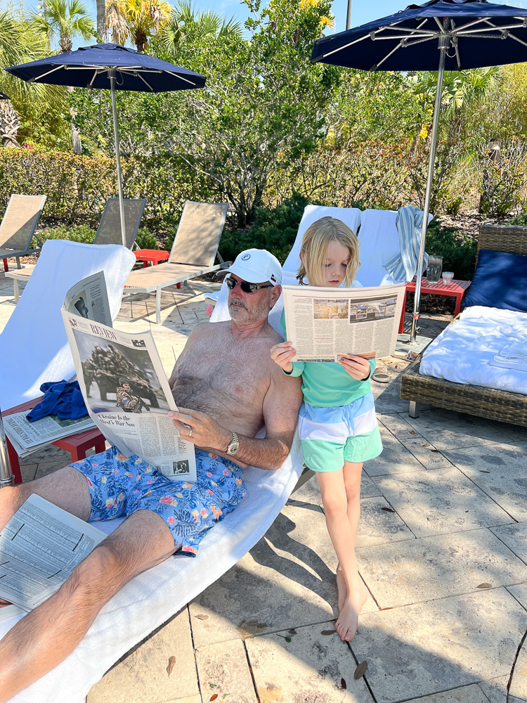 man and boy reading the paper poolside