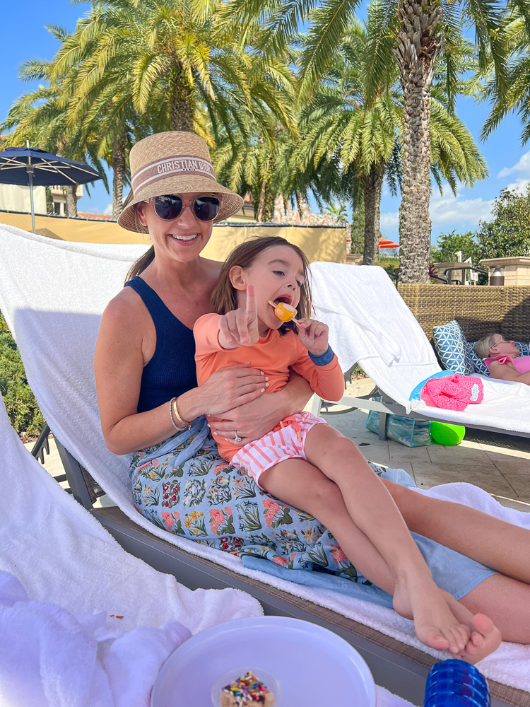mom with toddler boy in lap enjoying a popsicle by the pool