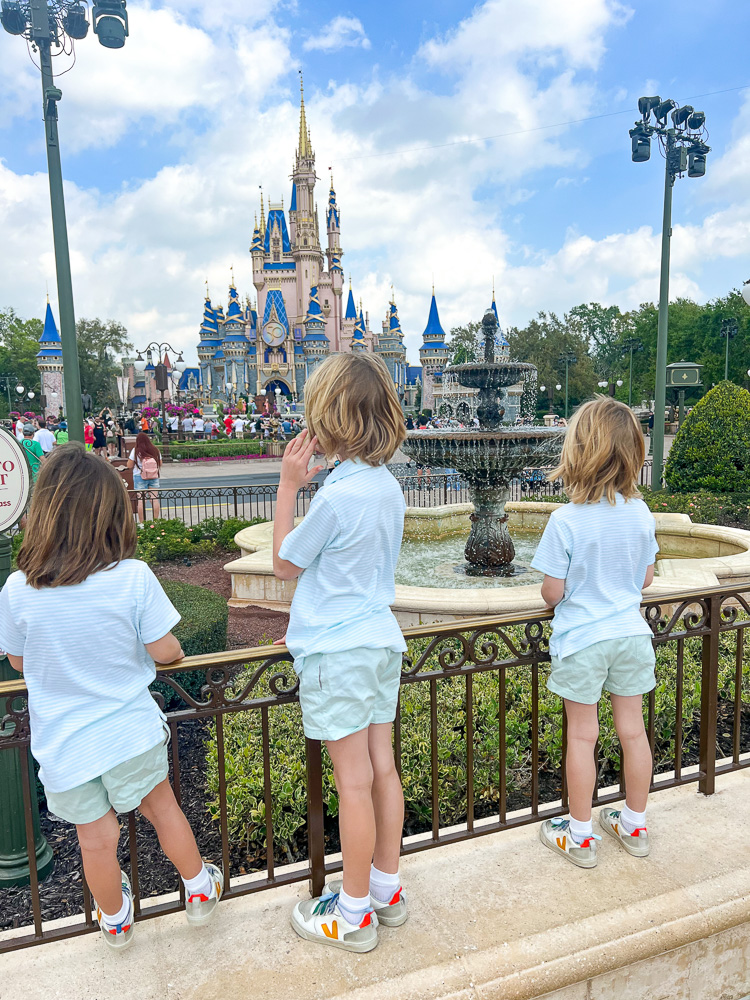 three boys standing looking at the castle at disney world