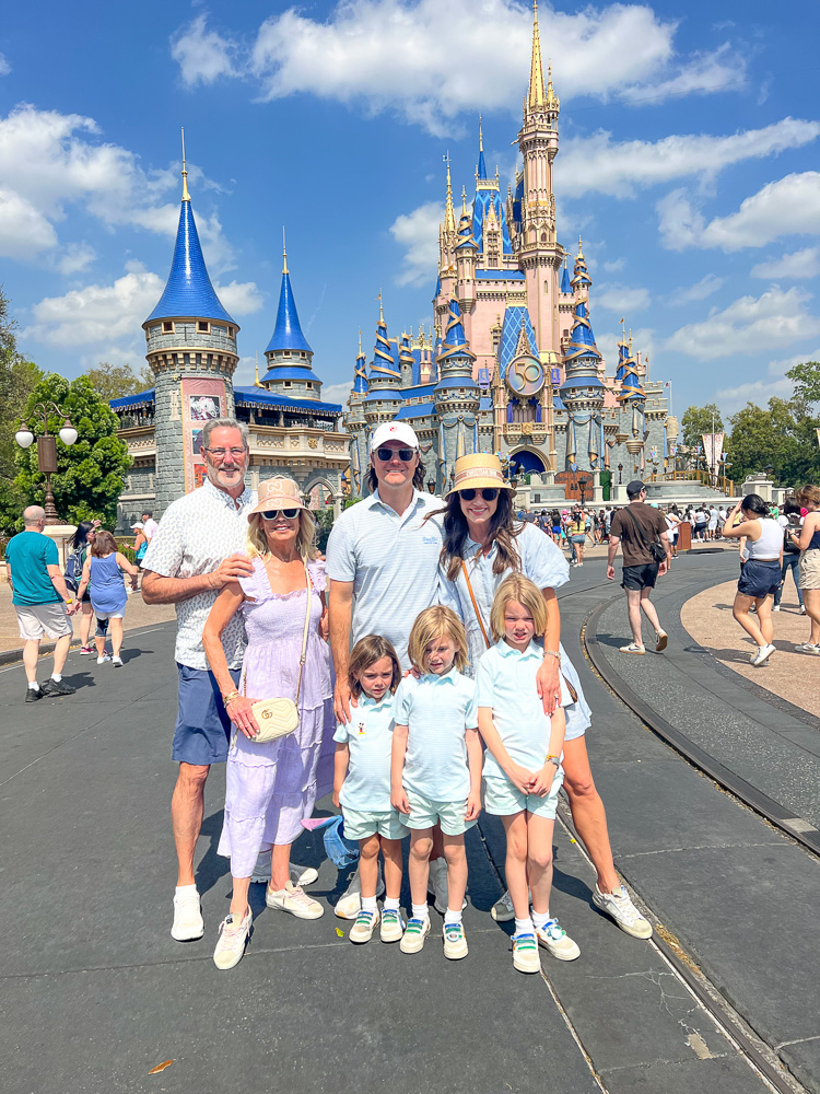 family group standing in front of castle at disney world