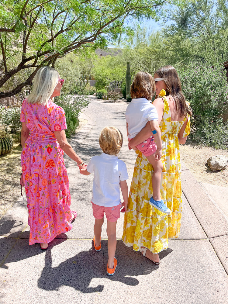 two women in floral long dresses walking with tow little boys