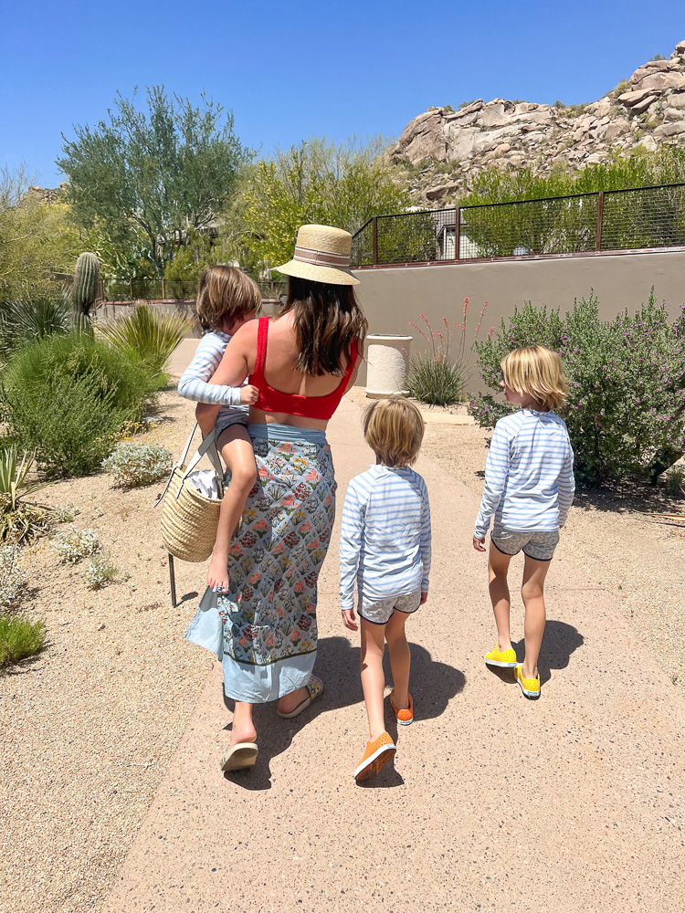 mom and three little boys in swimsuits walking