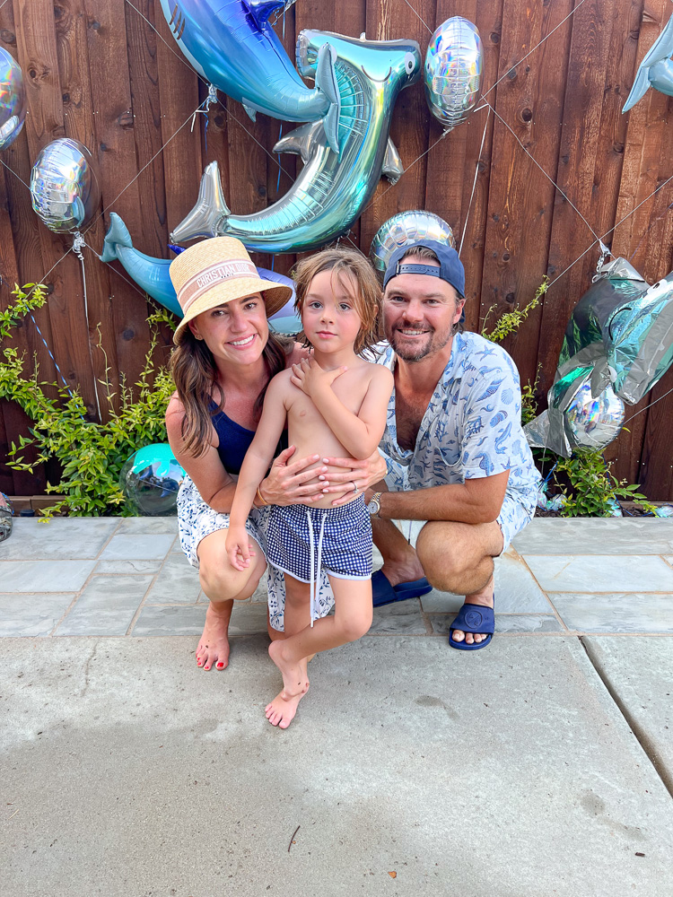 mom and dad with little boy in front of shark balloons