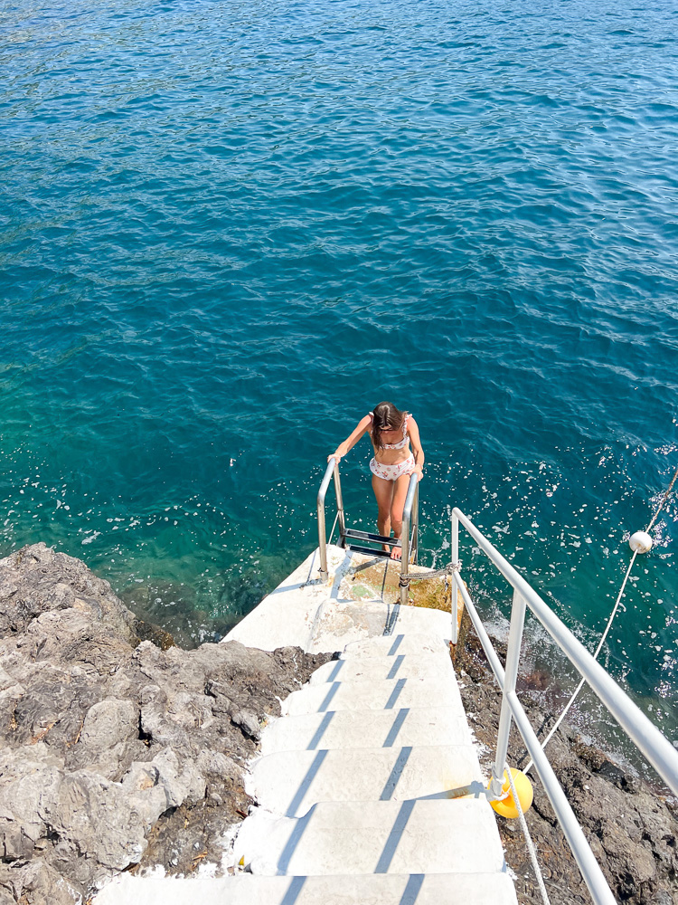 woman climbing stairs from the ocean to the beach club palazzo avino