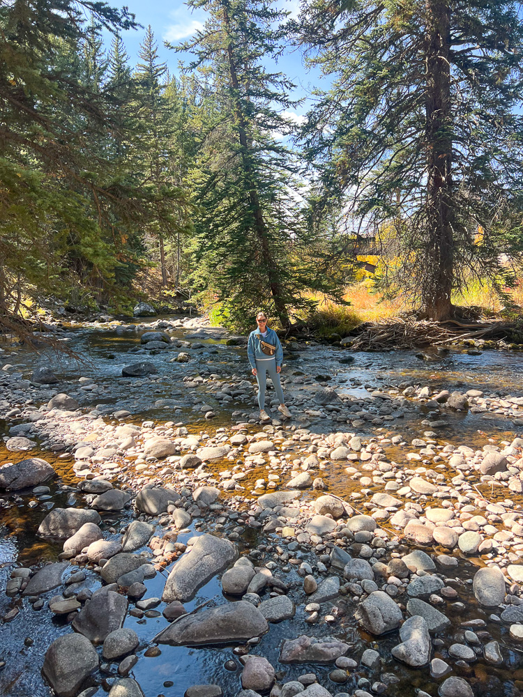 woman standing next to rocky river vail