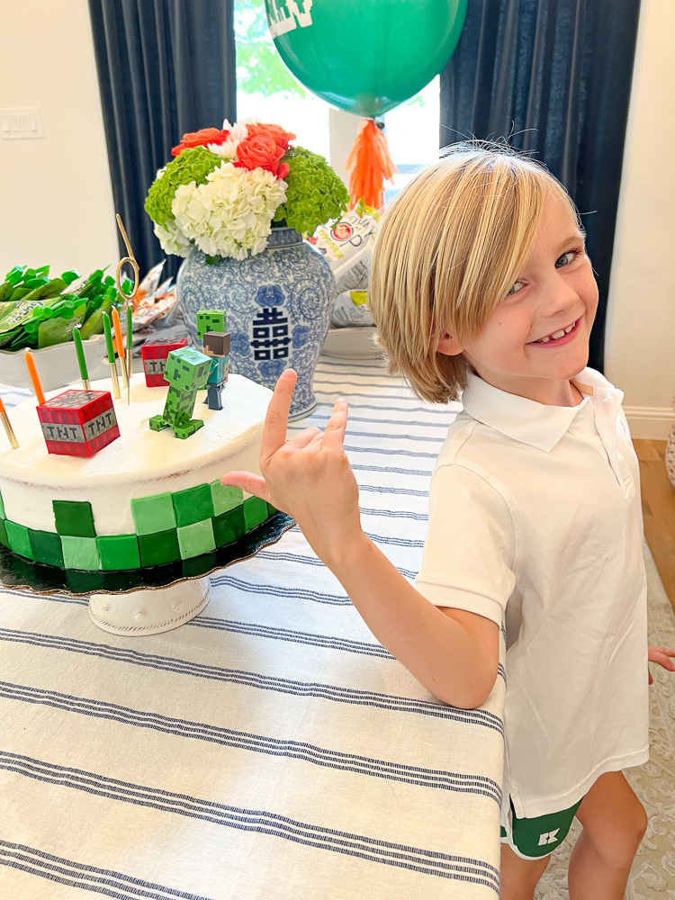 little boy standing by minecraft decorated birthday cake