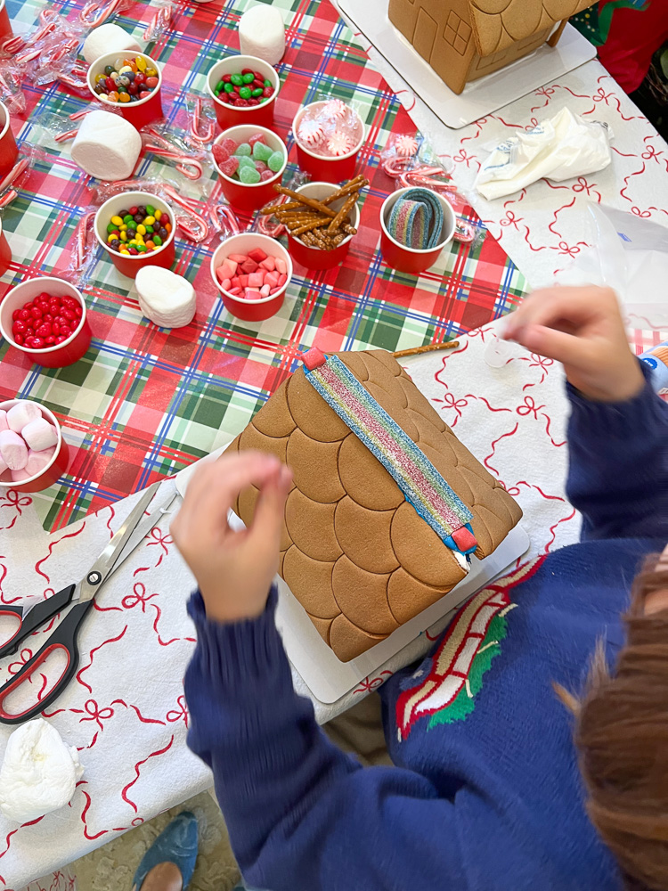 little hands decorating a gingerbread house