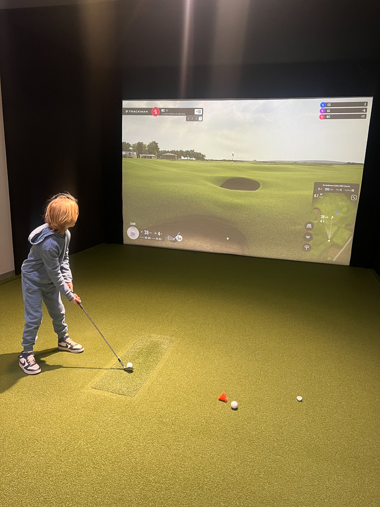 little boy playing golf indoor simulator birthday staycation omni pga resort