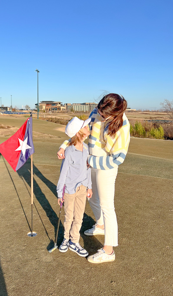 mom and son standing by a golf hole omni pga resort the swing