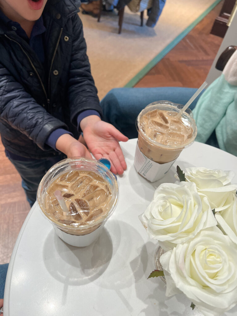 two iced coffees on a table with white roses