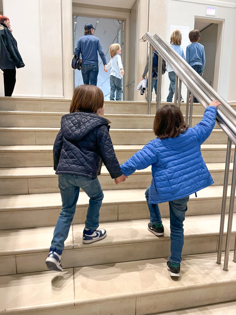 two little boys holding hands walking upstairs