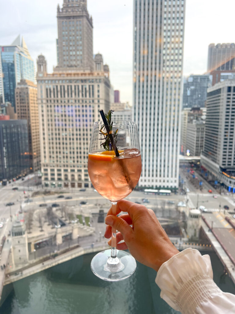 toasting with an aperol spritz with a view over downtown chicago