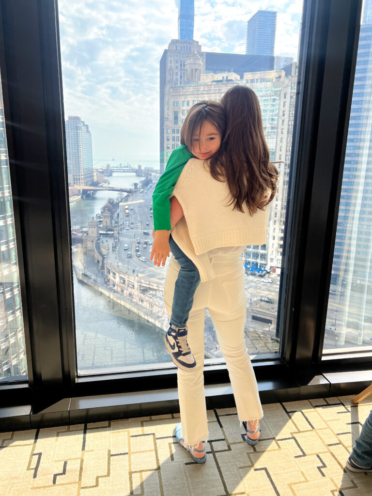 mom holding little boy in front of window looking over downtown chicago