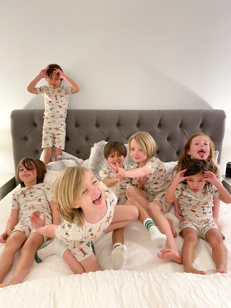 seven little kids in pajamas playing on a bed